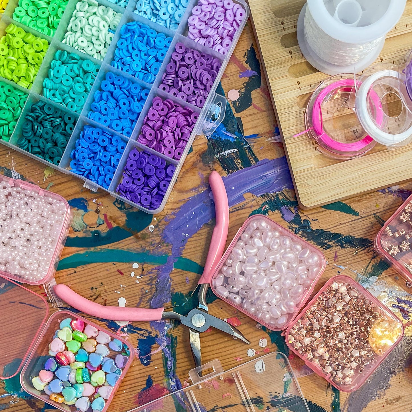 Colorful beads in transparent containers on a wooden surface with tools.