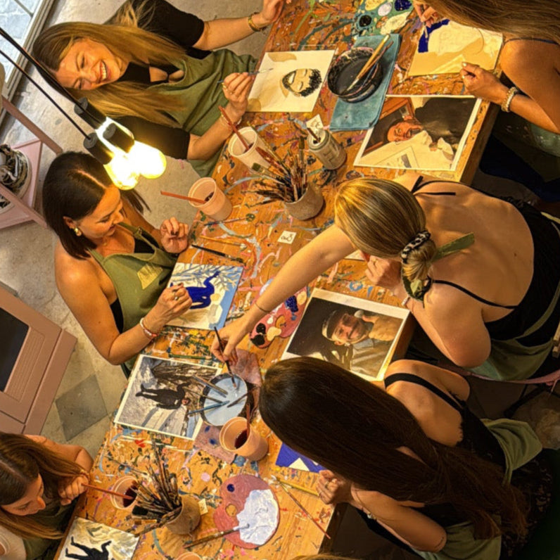 Group of women painting at a table with art supplies