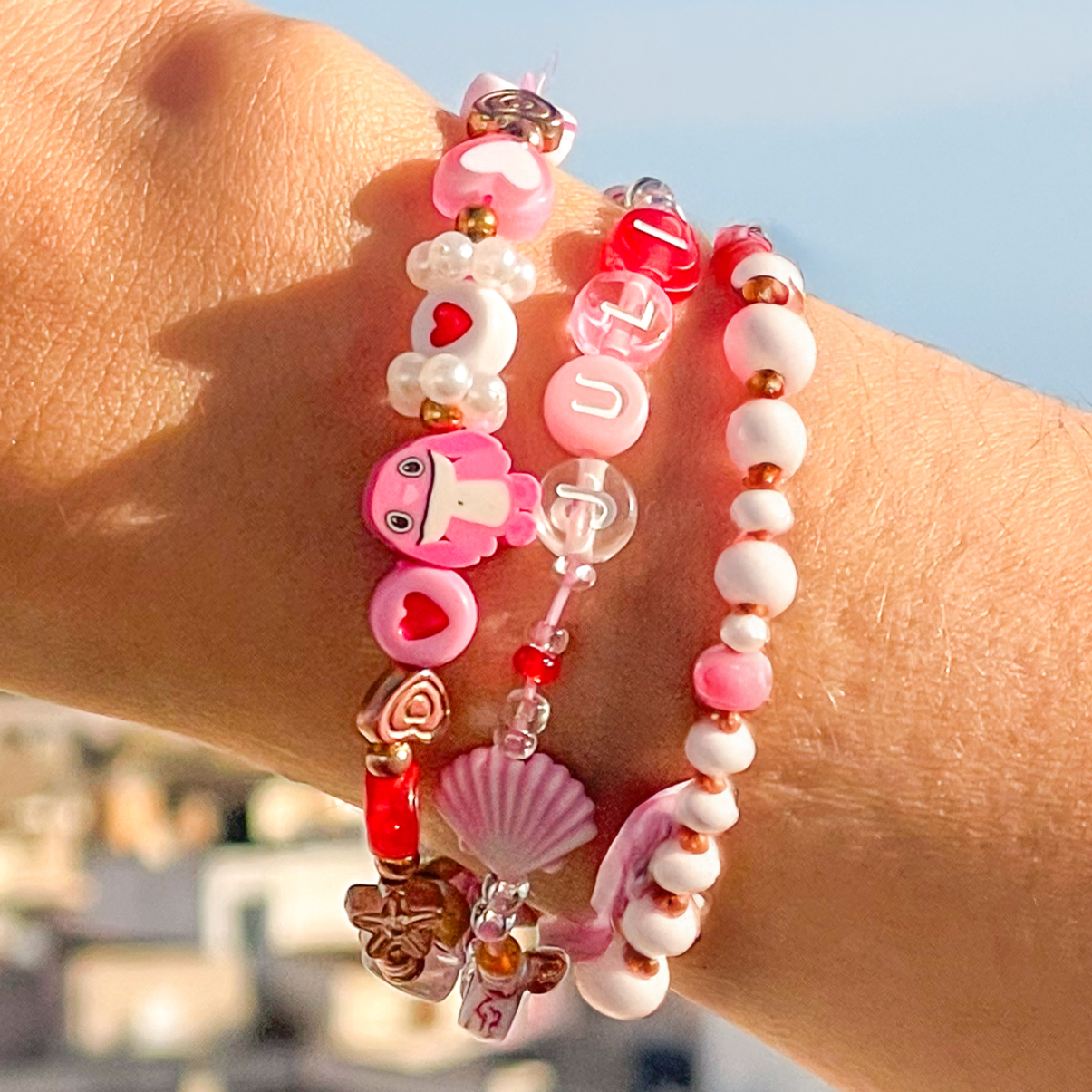 Close-up of a wrist wearing two colorful beaded bracelets with a blurred background