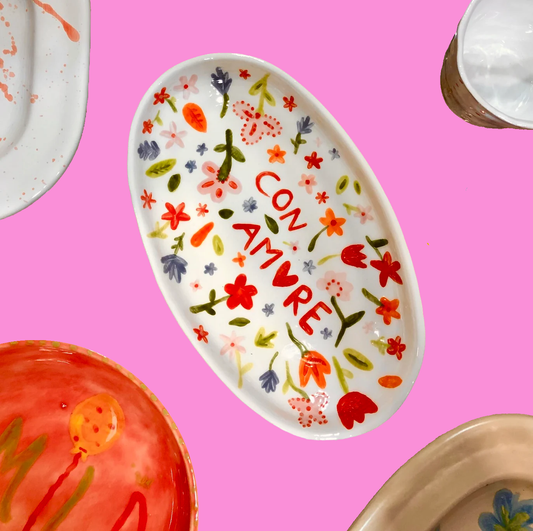 Decorative plate with floral patterns and 'CON AMORE' text on a pink background